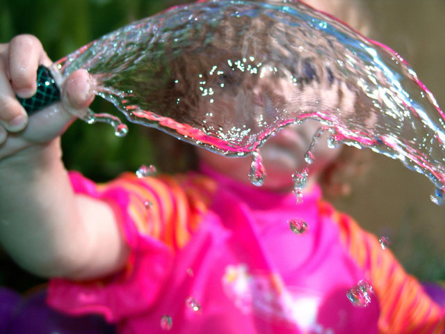 dítě drží hadici s vodou